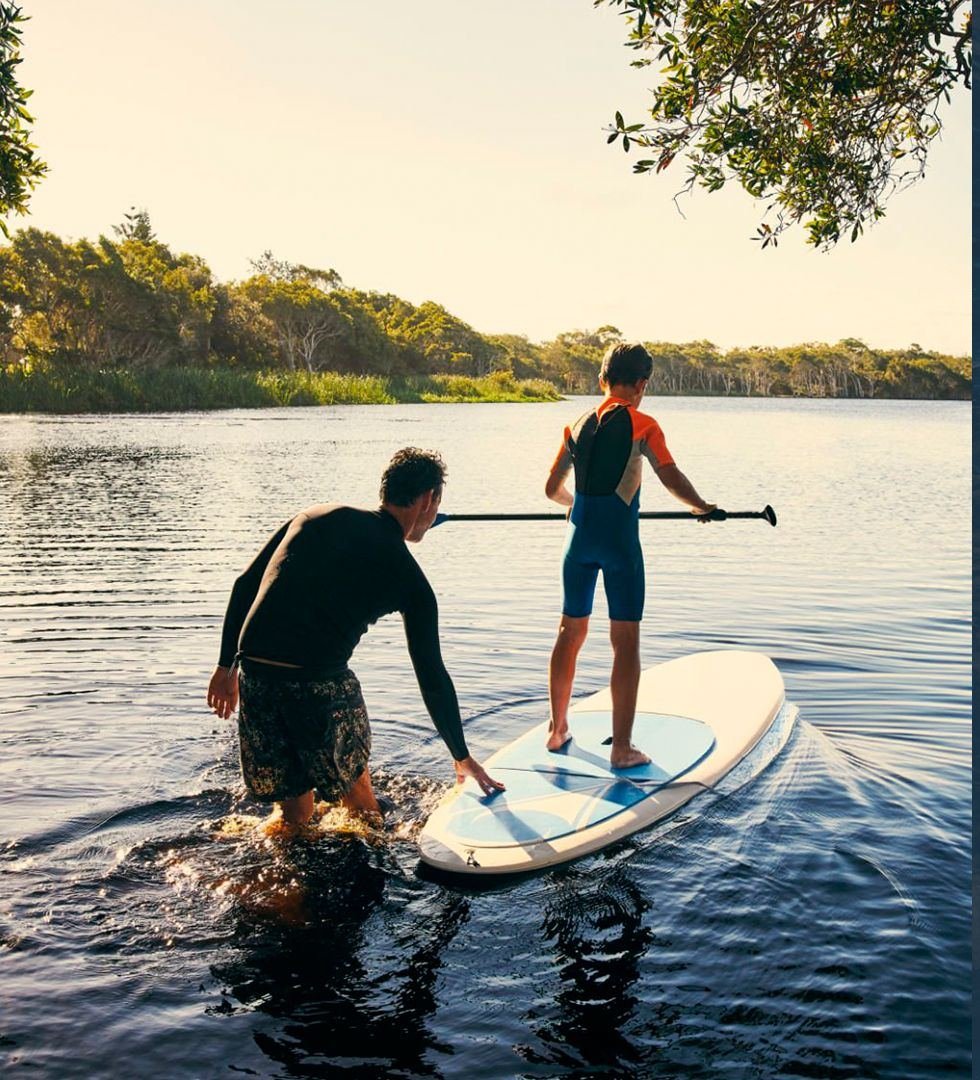 Pai e filho praticando stand up paddle no lago